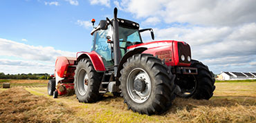 huge tractor collecting haystack in the field at nice blue sunny day