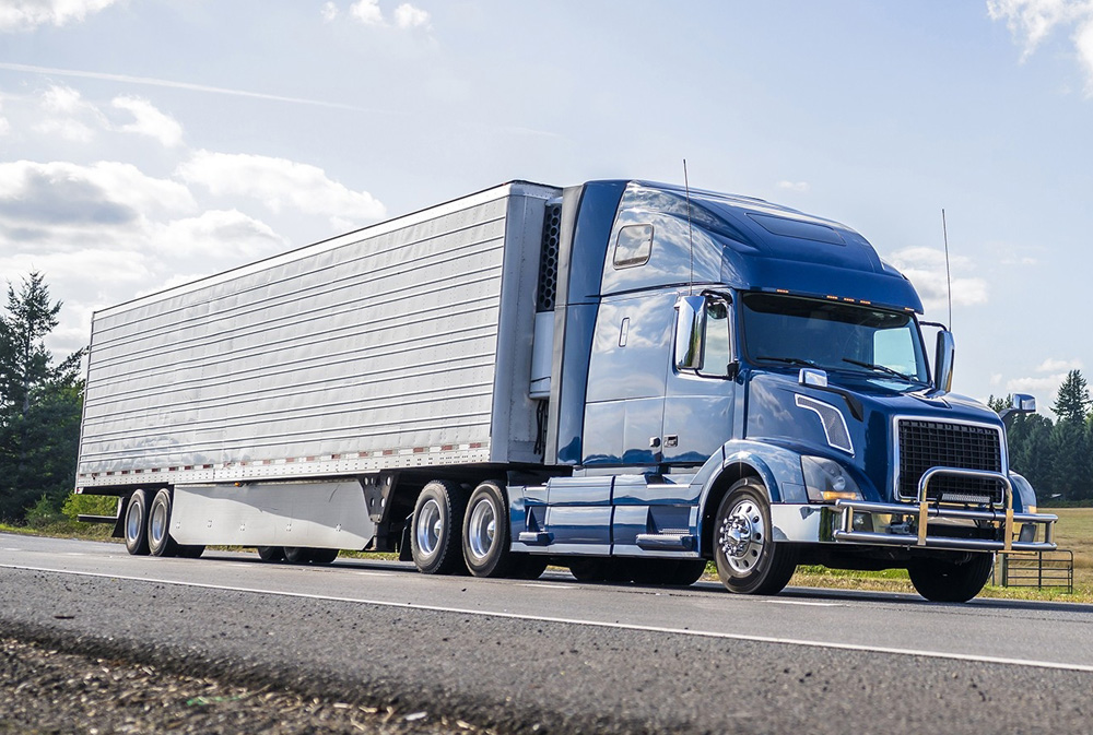 Red classic big rig semi truck with lot of chrome accessories with flat bed semi trailer stand on truck stop